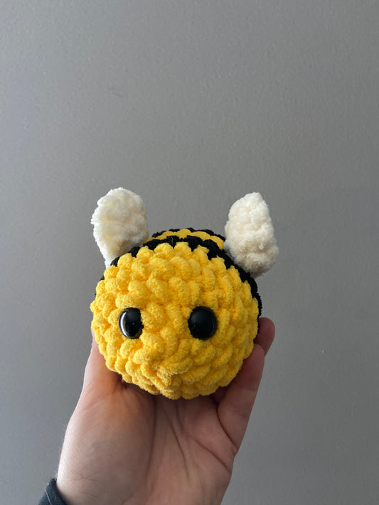 Crochet bee with yellow and black stripes, fuzzy wings, and a smiling face.