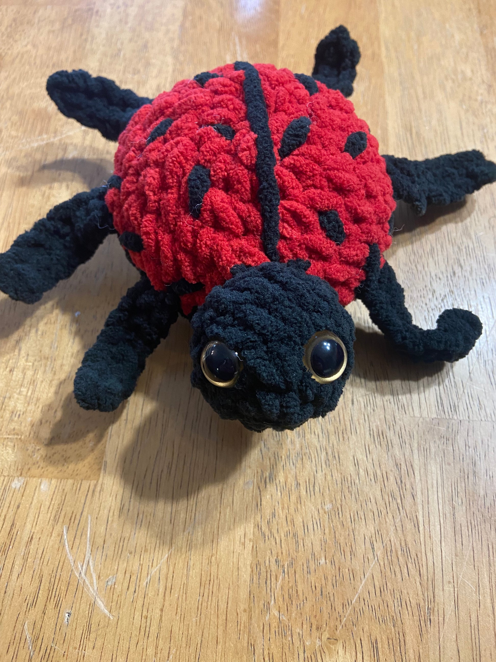 Handmade crochet ladybug plush toy with vibrant red and black colors, intricate crochet detailing, and adorable design.