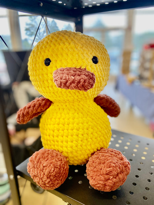 Crochet duck, with its wings spread out and a cute expression on its face.